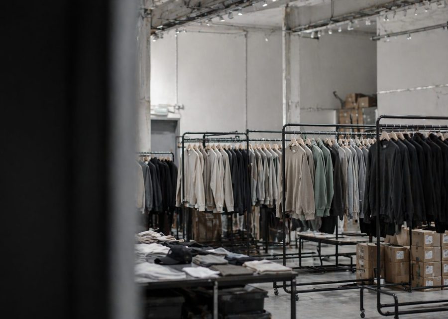 Warehouse with clothing racks full of neutral-colored jackets and boxes on the floor nearby.