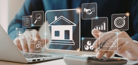 Businessperson calculating finances with a holographic house icon and real estate icons floating above the desk.